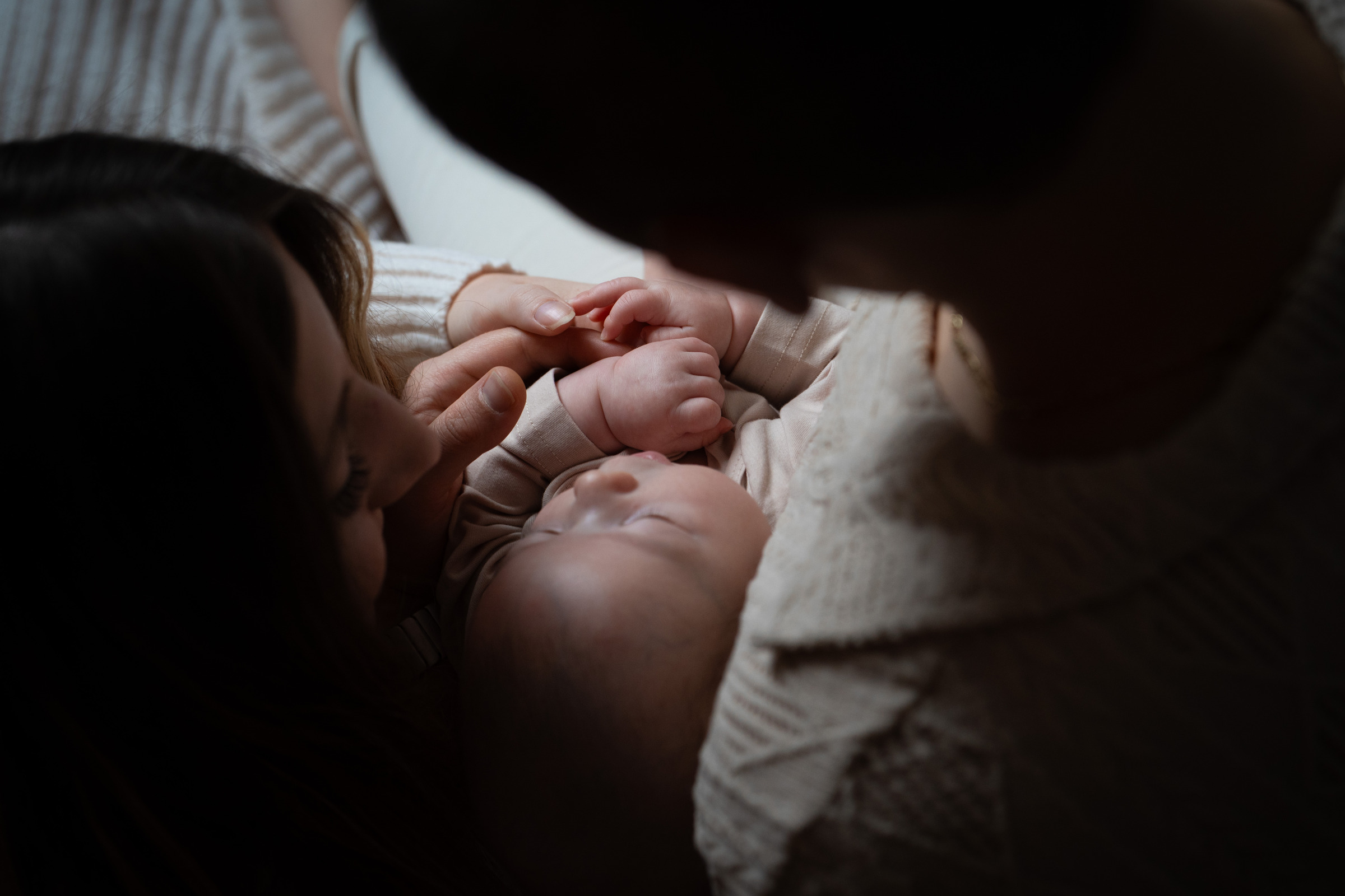 Un bébé entouré des mains de ses parents