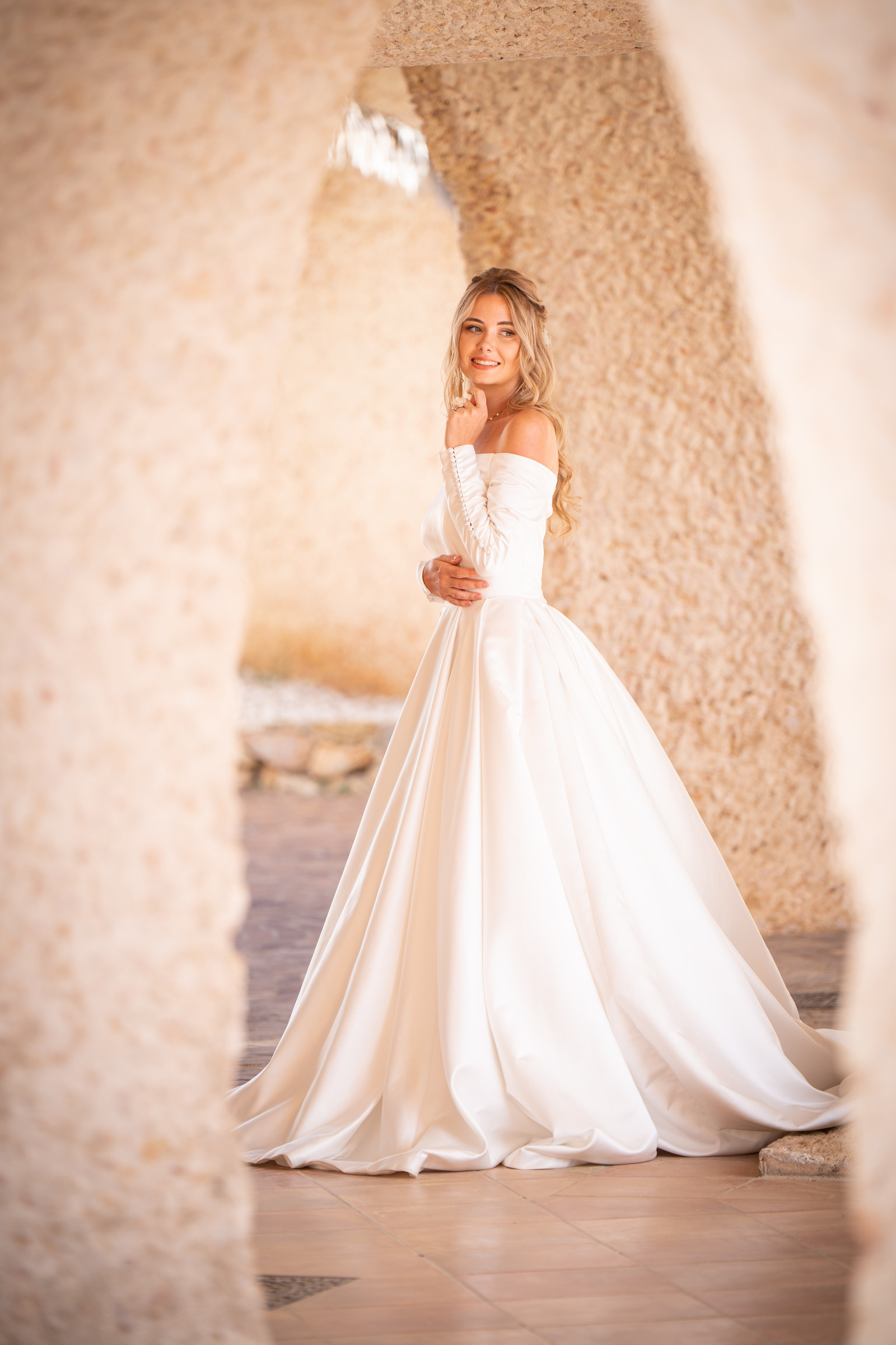 Portrait en robe de mariée sous une arche claire