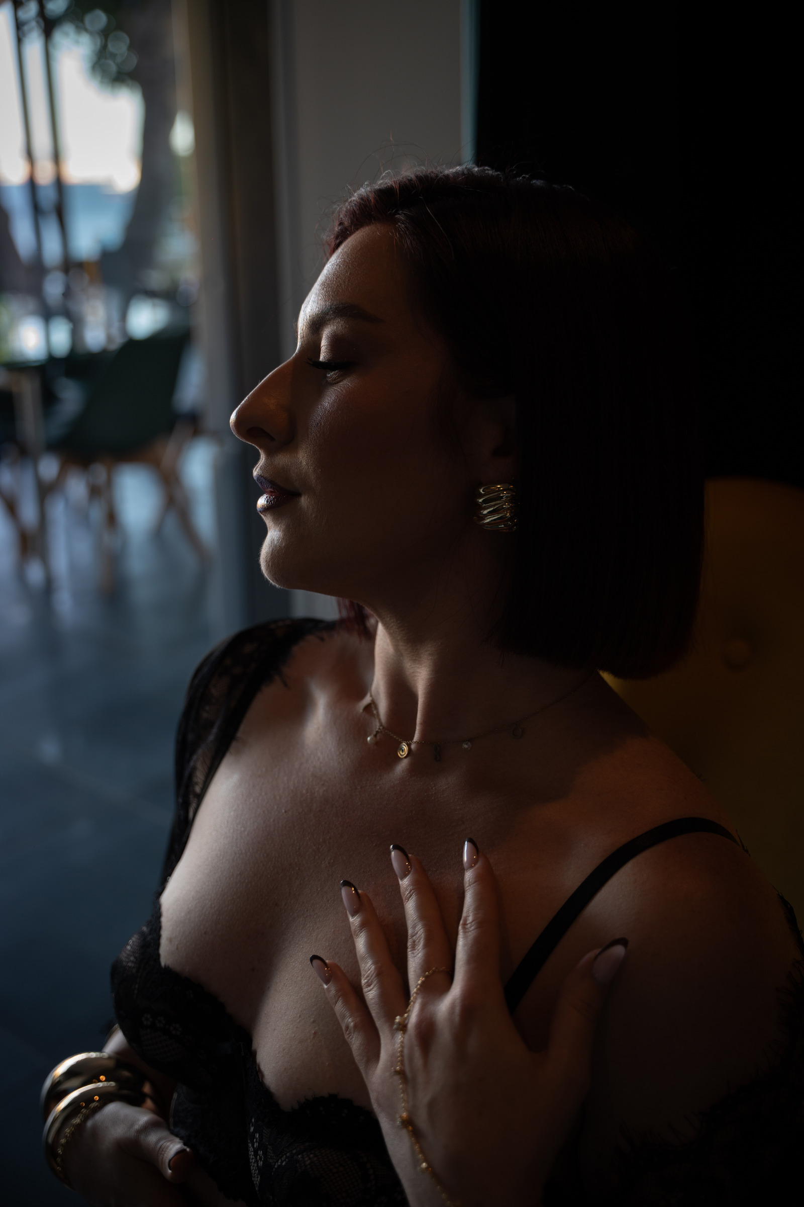 Portrait boudoir en lumière latérale, une main sur le décolleté