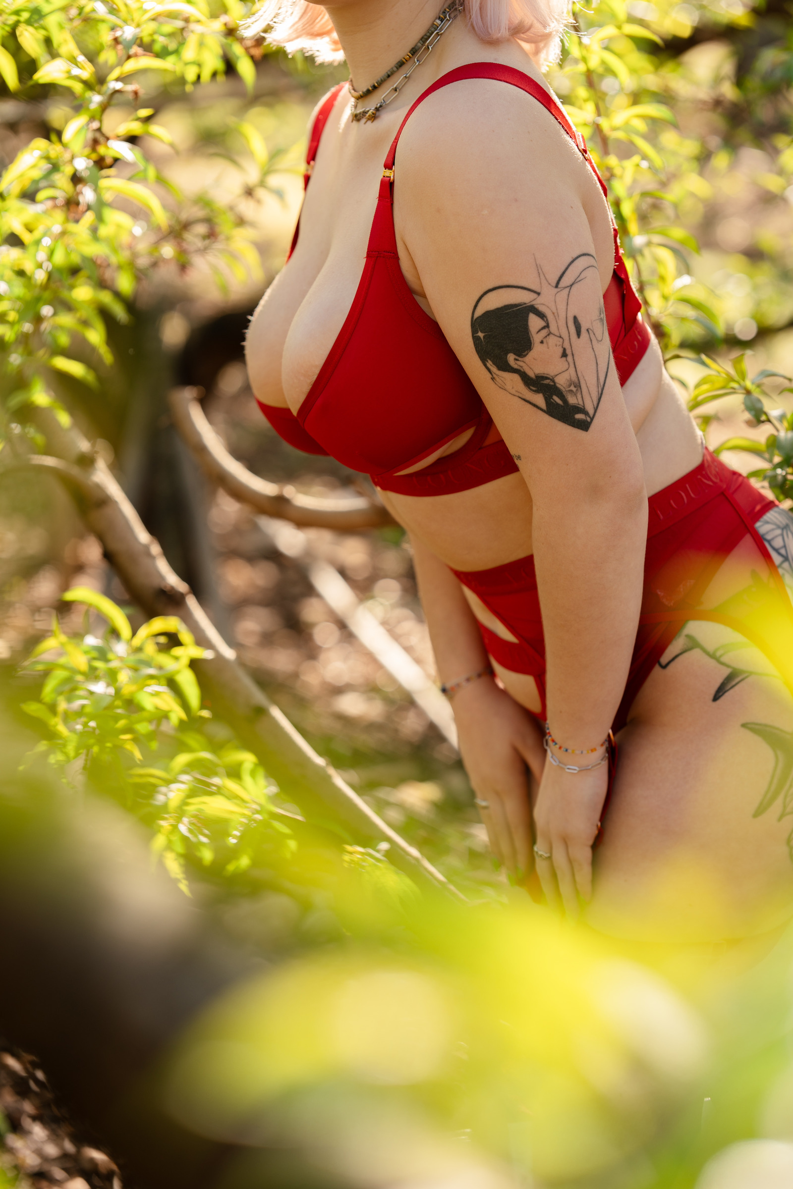 Séance boudoir en lingerie rouge dans la verdure