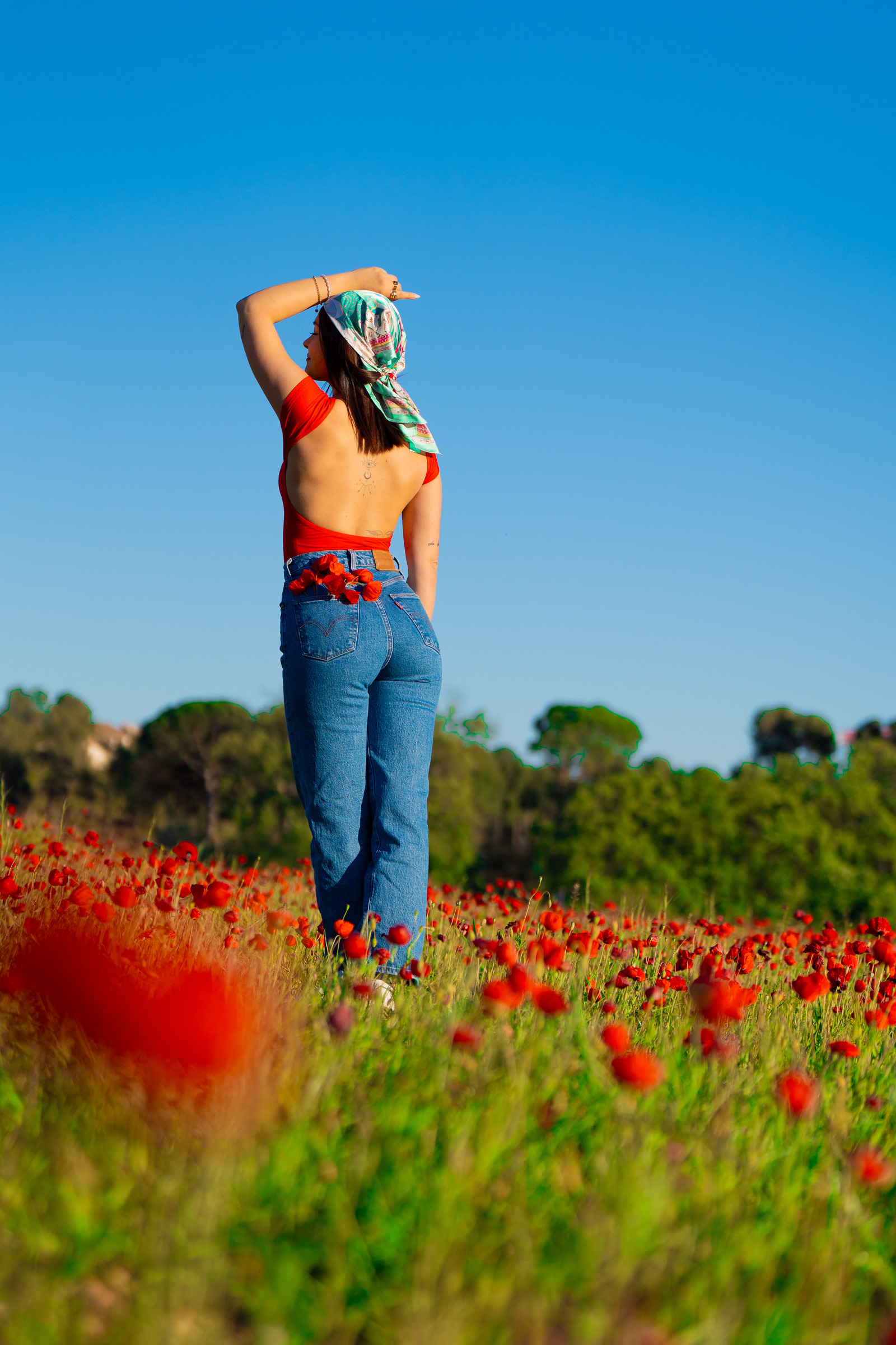 Portrait en jean et haut rouge dans un champ de coquelicots