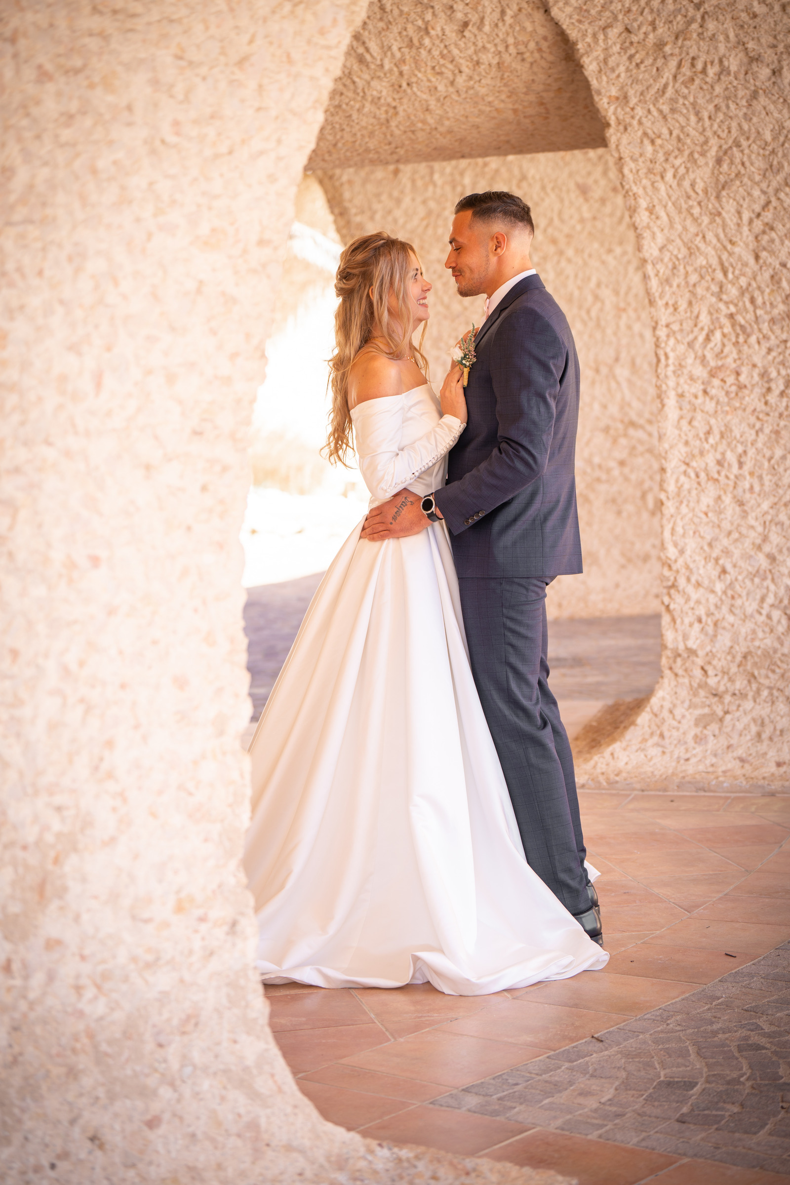 Un couple en tenue de mariage sous une arche claire