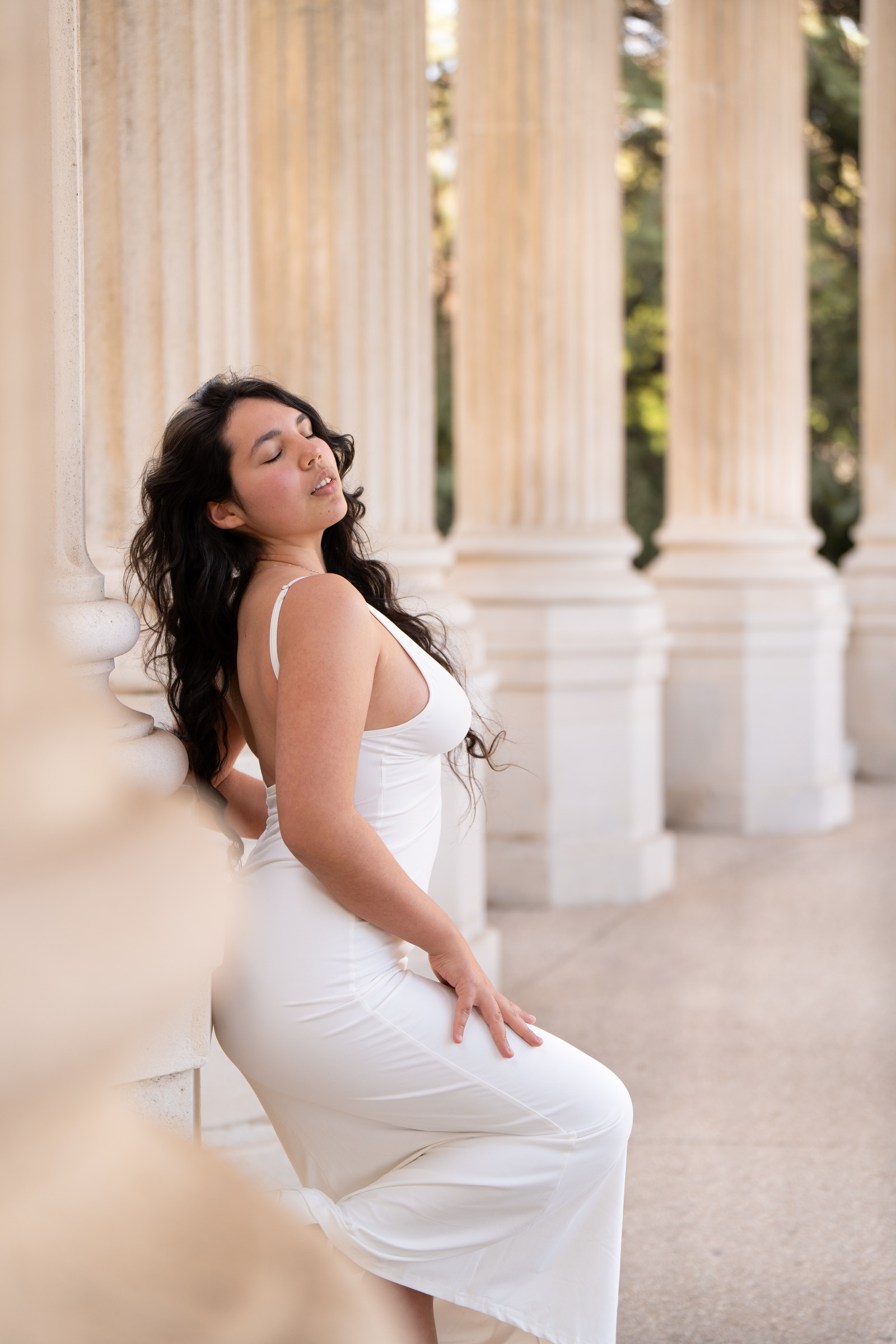 Portrait de grossesse en robe blanche près de colonnes