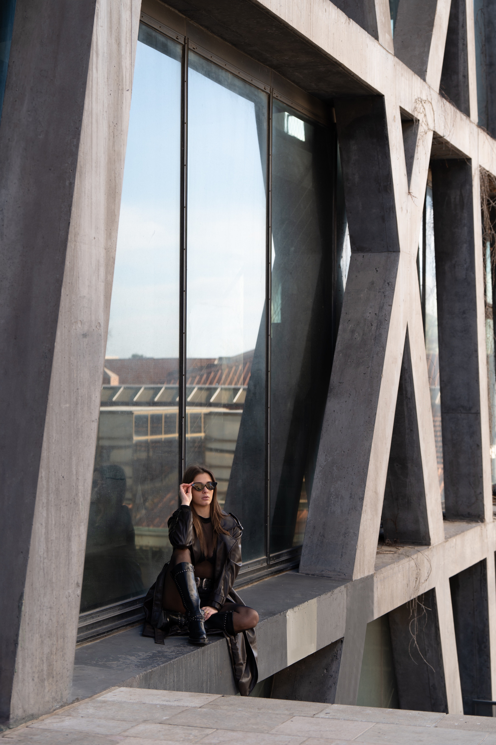 Portrait en tenue noire dans une architecture en béton