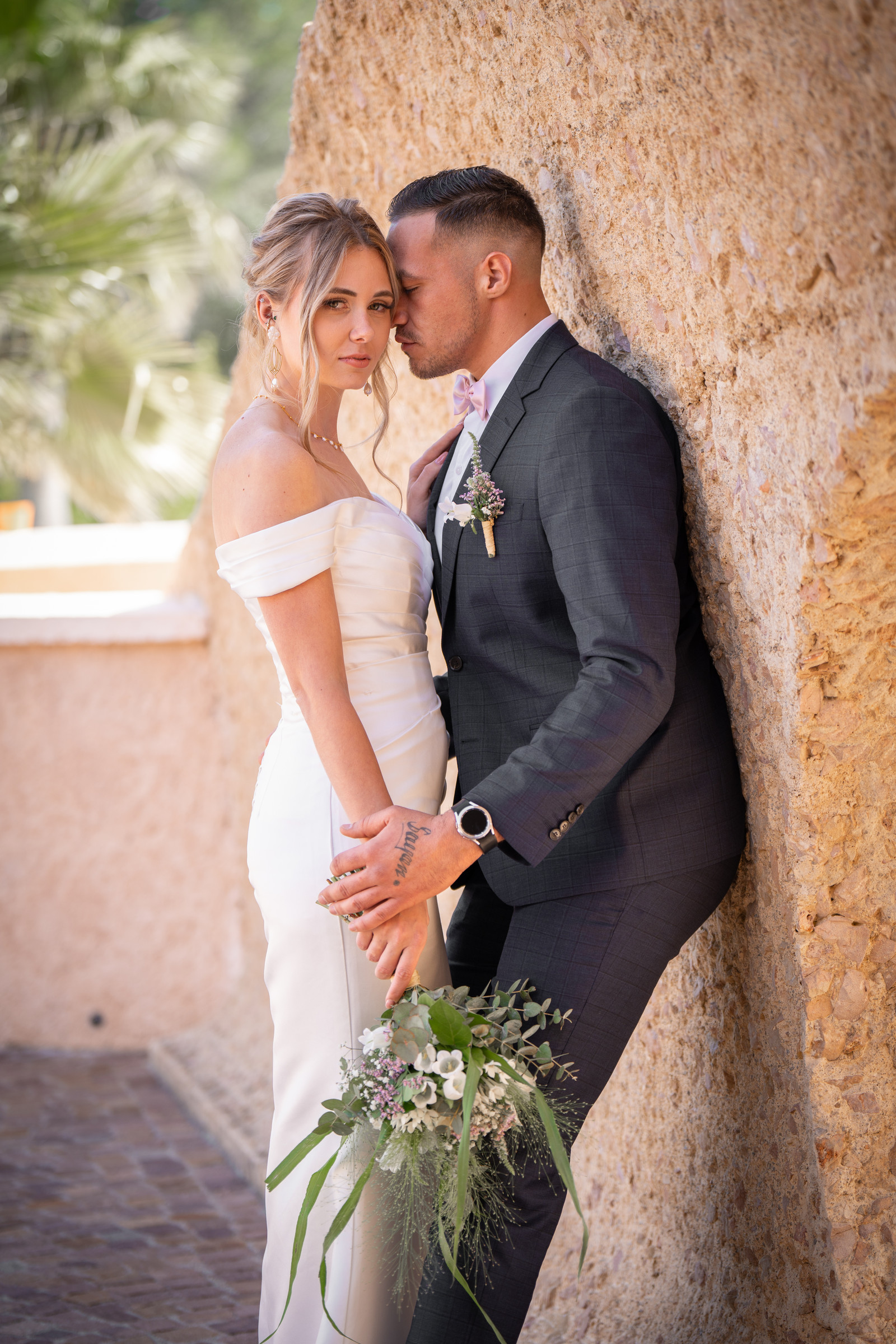 Un couple en tenue de mariage, bouquet à la main