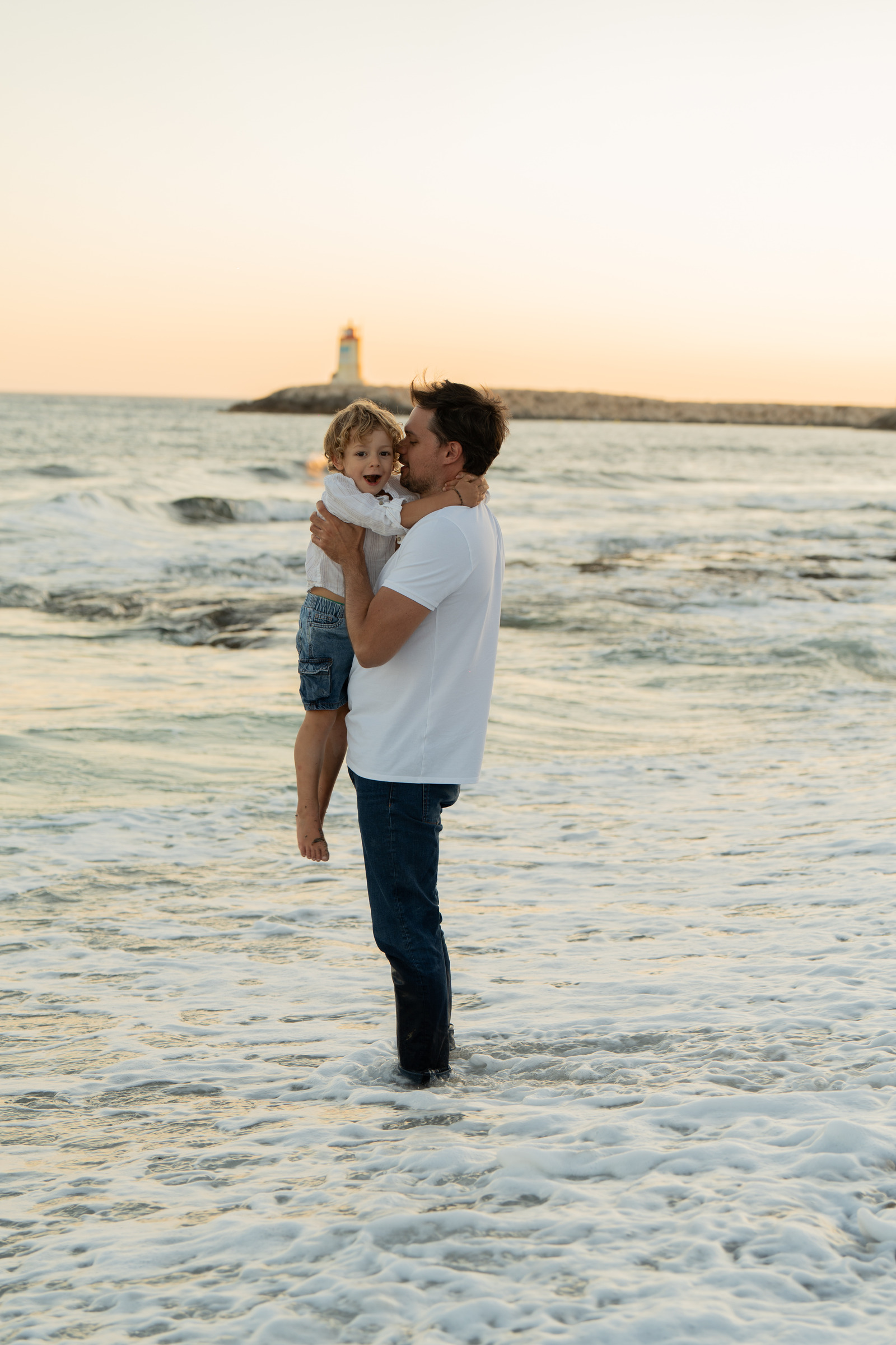 Un adulte porte un enfant au bord de la mer